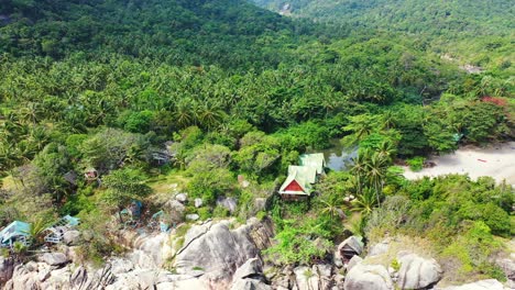 Cabañas-De-Resort-Construidas-Sobre-Grandes-Rocas-Con-Vista-Al-Mar-Rodeadas-De-Vegetación-Verde-Y-Bosque-De-Palmeras-De-Isla-Tropical-En-Tailandia