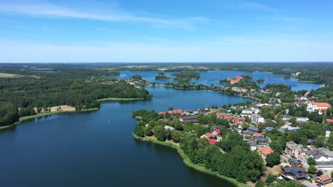 AERIAL:-Flying-Backwards-and-Revealing-Majestic-View-of-Trakai-Town-with-Blue-Color-Lake-and-Forest-in-the-Background