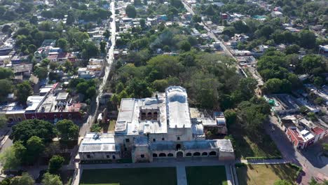 High-aerial-pull-back-and-tilt-up-on-the-Convent-de-San-Bernardino-in-Valladolid,-Yucatan,-Mexico-in-early-morning