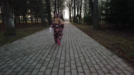 Three-years-old-toddler-girl-is-running-behind-the-camera-with-overalls-during-the-winter,-slowmotion-4k