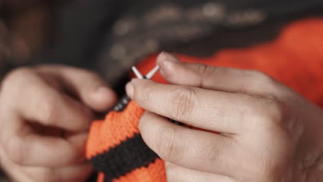 Close-up-of-woman's-hands-knitting-with-red-and-black-thread-and-needle-crafts