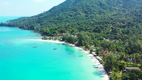 Mountains-with-palms,-wide-sandy-beach,-colorful-roofs-and-turquoise-sea-on-Thailand