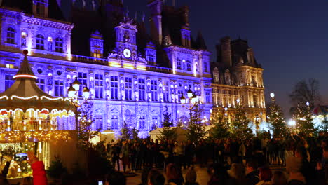 Weihnachtsbeleuchtete-Märkte-In-Einem-Wunderschönen-Teil-Von-Paris-Mit-Dominantem-Videomapping-Zum-Thema-Fallender-Schnee-Auf-Einem-Der-Hauptgebäude-Im-Zentrum,-Während-Eine-Menge-Besucher-Zuschauen