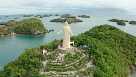 Orbital-Aerial-View-of-Statue-of-Christ-on-Pilgrimage-Island-at-Hundred-Islands-National-Park,-Philippines-in-4K