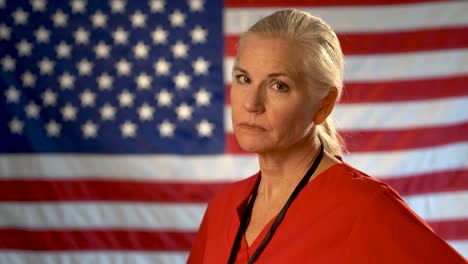 Medium-tight-portrait-of-the-back-of-blonde-nurses-head-as-she-turns-quickly-and-looks-angry-and-concerned-with-out-of-focus-American-flag