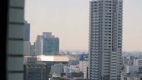 View-from-a-high-rise-window-of-the-urban-structures-in-the-city,-stable-handheld-shot