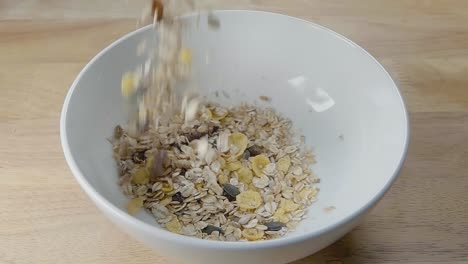 Slow-Motion-Slider-Shot-of-Pouring-Muesli-into-a-White-Cereal-Bowl-on-a-Kitchen-Counter-for-Breakfast