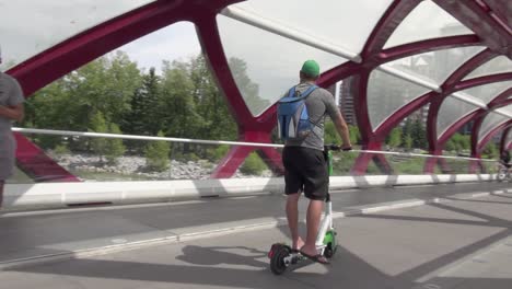 Tracking-pan-as-men-ride-scooters-across-urban-Peace-Bridge-in-Calgary