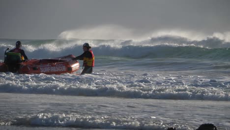 Surf-Lebensrettung-–-Zwei-Rettungsschwimmer-Mit-Schwimmweste-überwinden-Die-Rauen-Wellen,-Während-Sie-Das-Rettungsboot-Ziehen-–-Currumbin,-Gold-Coast,-Australien