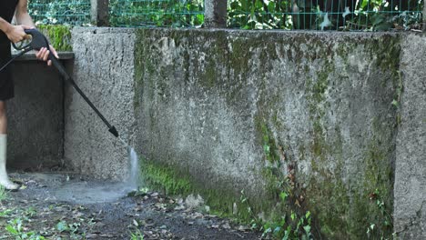 Man-using-electric-powered-pressure-washer-to-power-wash-dirty-wall