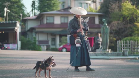 Famous-Japanese-Samurai-Flute-Man-Playing-Shakuhachi-With-His-Samurai-Dog-In-Front-Of-Tourists-In-Maruyama-Park-Next-To-The-Yasaka-Shrine-In-Kyoto,-Japan