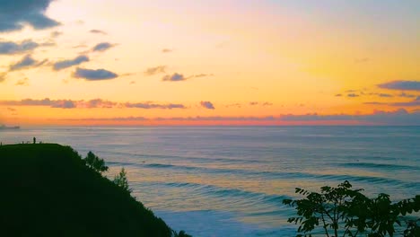 HD-Hawaii-Kauai-slow-motion-wide-shot-pan-left-to-right-from-a-person-on-a-lookout-point-in-frame-left-to-the-ocean-with-a-beautiful-sky-near-sunset