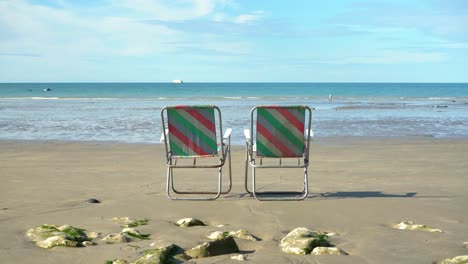 4K-Aufnahme-Von-Zwei-Leeren-Stühlen-An-Einem-Strand-In-Der-Normandie-Mit-Blauem-Himmel
