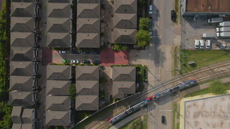 Aerial-view-of-neighborhood-near-train-tracks-with-train-passing-in-Houston,-Texas,-USA