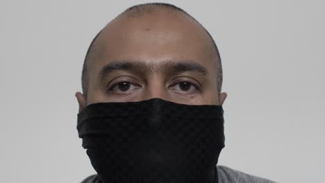 Erwachsenes-Britisches-Asiatisches-Männchen,-Das-Drinnen-Eine-Balaclava-Gesichtsmaske-Aufsetzt