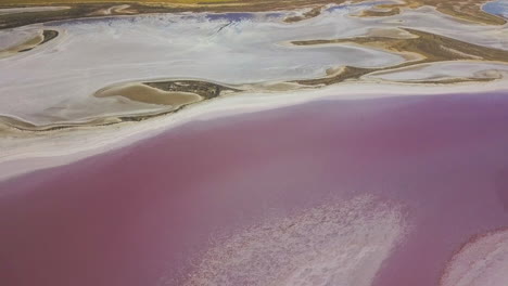 Drone-flying-over-the-bright-pink-waters-of-Lake-Tyrrell,-Australia