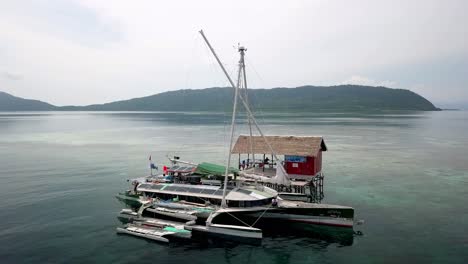 Bigkanu-Trimaran-Segelboot-Kreuzfahrt,-Stationiert-Im-Dorf-Friwen,-Mit-Passagieren-An-Deck,-Aufnahme-Aus-Der-Luft