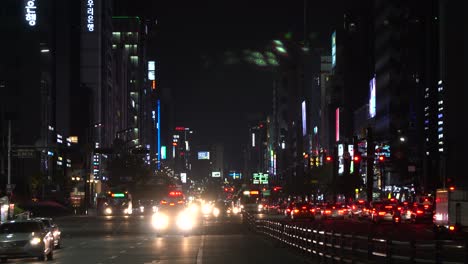 Nacht-Seoul,-Krankenwagen-Mit-Eingeschalteten-Sirenenlichtern-Bewegt-Sich-Auf-Die-Kamera-Zu,-Nachdem-Er-Die-Kreuzung-Am-Bahnhof-Gangnam-Passiert-Hat,-Seoul,-Südkorea.-Autos-Warten-Auf-Rotes-Signallicht.-Nachtstadtbild-Von-Seoul