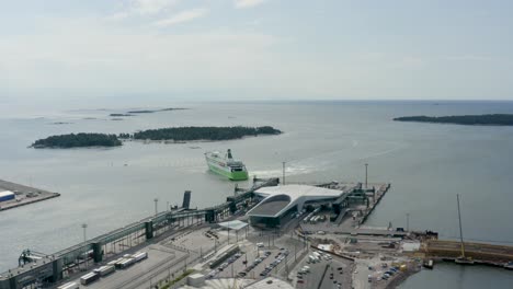 Slow-aerial-pan-high-above-port-in-Helsinki,-Finland-with-large-ship-departing