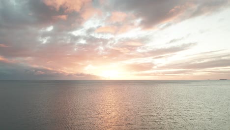 Epic-Sunset-over-Pacific-Ocean,-flying-backwards-over-open-sea-during-sundown