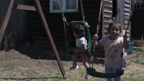 Cute-Baby-And-Older-Sister-Together-On-Swing-Set-In-The-Garden