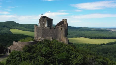 Drone-footage-about-Ruins-of-an-old-castle-from-the-middle-ages-at-Holloko,-Hungary-Drone-circles-left
