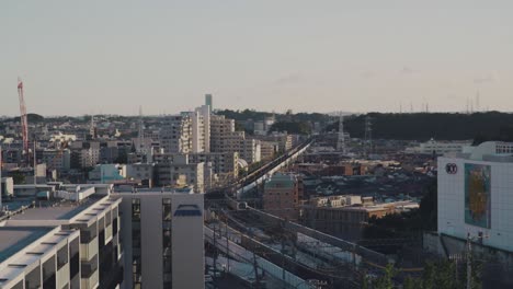 Train-Approaching-On-The-Railway-With-Cityscape-View-Of-Yokohama-In-Japan---high-angle-shot