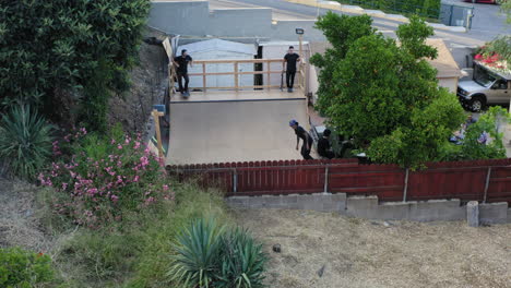 Los-Angeles-skaters-on-homemade-backyard-mini-ramp,-aerial-view