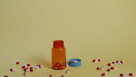 Slow-motion-wide-shot-of-pills-as-they-fall-vertically-towards-an-open-pill-bottle-and-lid