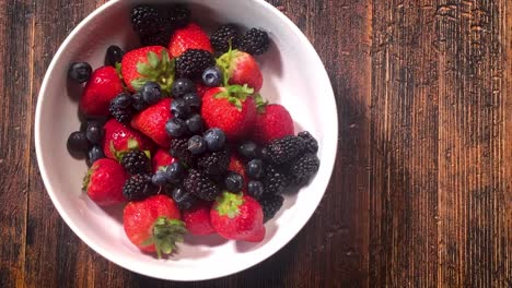 Geben-Sie-Eine-Frische-Beerenmischung-Aus-Erdbeeren,-Blaubeeren-Und-Brombeeren-In-Die-Schüssel-Auf-Dem-Tisch