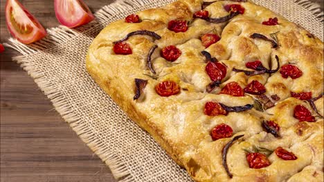 Traditional-Italian-Focaccia-with-pepperoni,-cherry-tomatoes,-black-olives,-rosemary-ando-onion---homemade-flat-bread-focaccia