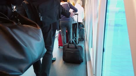 Passengers-in-a-queue-shuffle-along-boarding-bridge-to-enter-airplane
