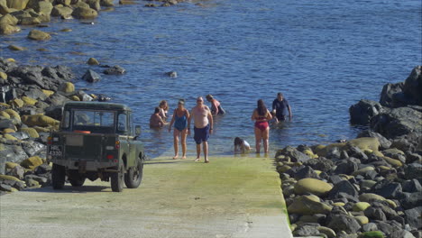 Group-of-people-wade-in-water-near-boat-ramp-at-Cape-Cornwall