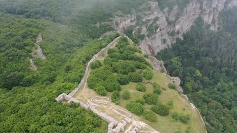 Aerial-view-of-an-ancient-Madara-fortress-with-clouds-coming-from-the-sides