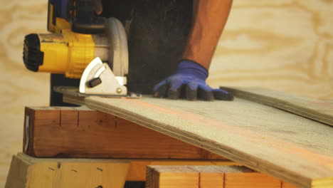 Young-man-uses-a-power-saw-to-trim-the-size-of-a-piece-of-plywood-that-he-is-using-to-build-a-homemade-backyard-skateboard-ramp