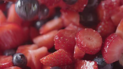 Strawberries-and-blueberries-mixed-in-a-bowl,-slow-motion