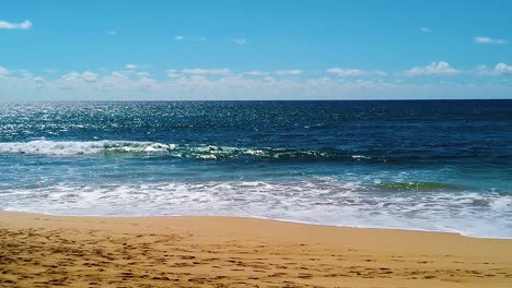 HD-Hawaii-Kauai-slow-motion-of-beautiful-backlit-shot-of-ocean-waves-breaking-on-beach-in-lower-third,-ocean-in-middle-third,-clouds-at-horizon-and-blue-sky-in-upper-third-version-two