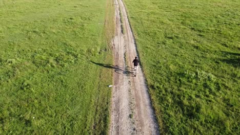Aerial-footage-of-a-male-ridding-his-bike-on-a-country-road-on-a-sunny-summer-day