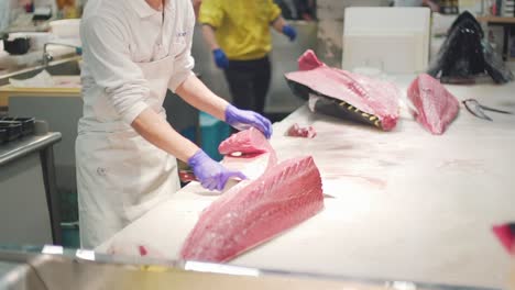 Person-Cutting-Fresh-Bluefin-Tuna-Using-A-Butcher's-Knife-In-Front-Of-Public-At-The-Toretore-Ichiba-Fish-Market,-Wakayama-Japan