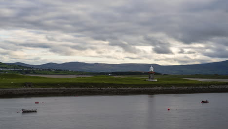 Zeitraffer-Eines-Leuchtturmhafens-Mit-Geparkten-Booten-Im-Vordergrund-Und-Sich-Schnell-Bewegenden-Wolken-Am-Himmel-In-Irland
