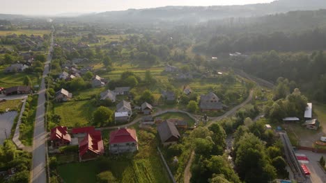 Aerial-view-towards-idyllic-houses,-in-the-Shayan-town,-sunny,-hazy-morning,-in-the-Carpathian-Mountains,-Ukraine---descending,-drone-shot