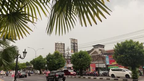 Busy-Everyday-Traffic-in-Yogyakarta-City,-Java-Island,-Indonesia,-Shops-and-Cars-Under-Cloudy-Sky-During-Rainy-Season