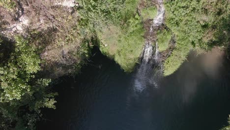 Aerial-View-of-a-Hidden-Waterfall-Lagoon-Surrounded-by-Foliage