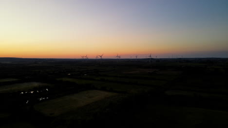 Windkraftanlagen-Auf-Dem-Riesigen-Feld---Drehende-Propeller-Bei-Sonnenuntergang-Im-Landkreis-Puck,-Polen---Aufsteigende-Drohnenaufnahme