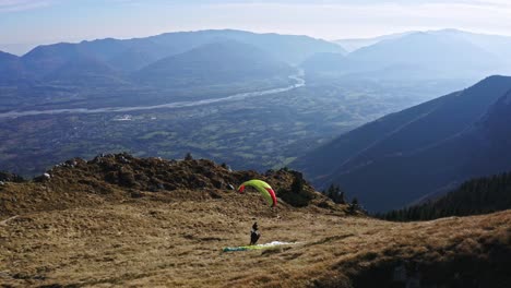 man-with-paraglider-runs-and-glides-over-Pizzocco-mountain,-adventure-sport