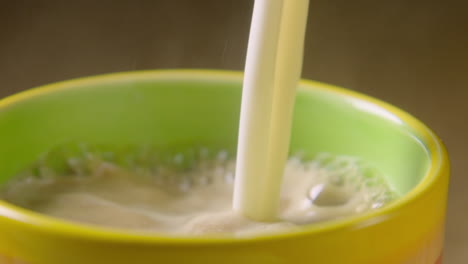 PAN-LEFT,-Frothy-oat-milk-is-poured-into-a-steaming-colourful-mug,-60fps