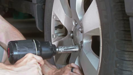 Mechanic-tigtening-lug-nuts-on-car-tire-with-impact-wrench,-Slow-Motion