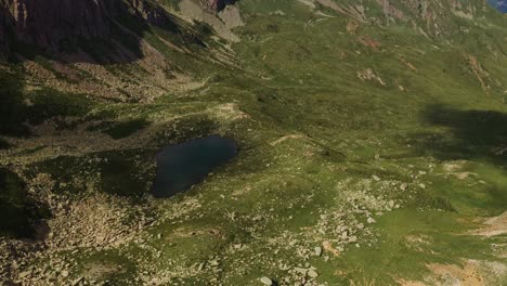 Looking-down-at-a-small-lake-secluded-in-between-mountains-of-the-mountain-range-Lagorai,-Italy