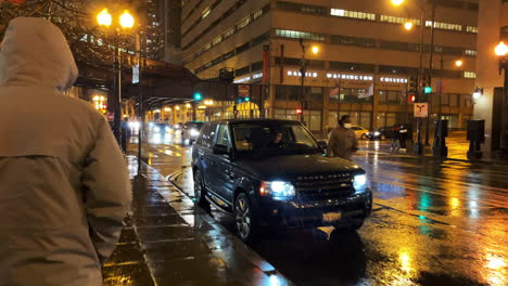 Anonymous-man-in-white-coat-and-hoodie-strolling-downtown-chicago-at-rainy-night