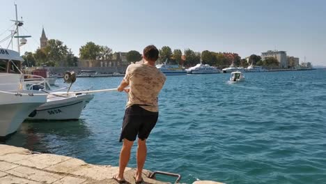 Un-Pescador-Está-Tirando-De-Un-Barco-Atracado-En-El-Puerto-De-Zadar,-Croacia